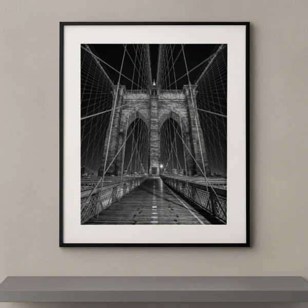 Tableau noir et blanc du Brooklyn Bridge photographié de nuit en perspective symétrique