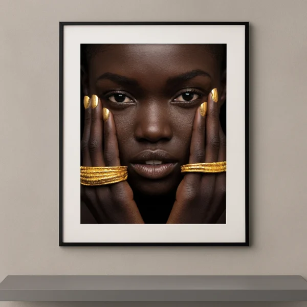 Portrait artistique de beauté ethnique contemporaine avec bijoux dorés, regard intense et composition photographique minimaliste sur fond noir.
