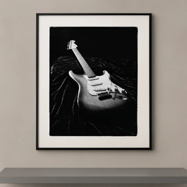 Tableau noir et blanc d'une guitare électrique Fender Stratocaster posée sur du velours noir