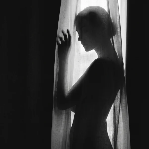 Derrière le Voile — silhouette féminine à travers un rideau translucide en contre-jour, noir et blanc, art mural premium