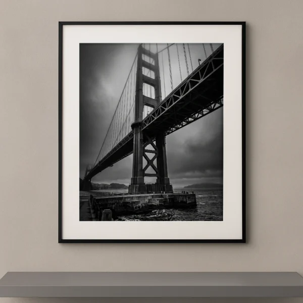 Tableau noir et blanc du Golden Gate Bridge enveloppé de brume sous un ciel dramatique