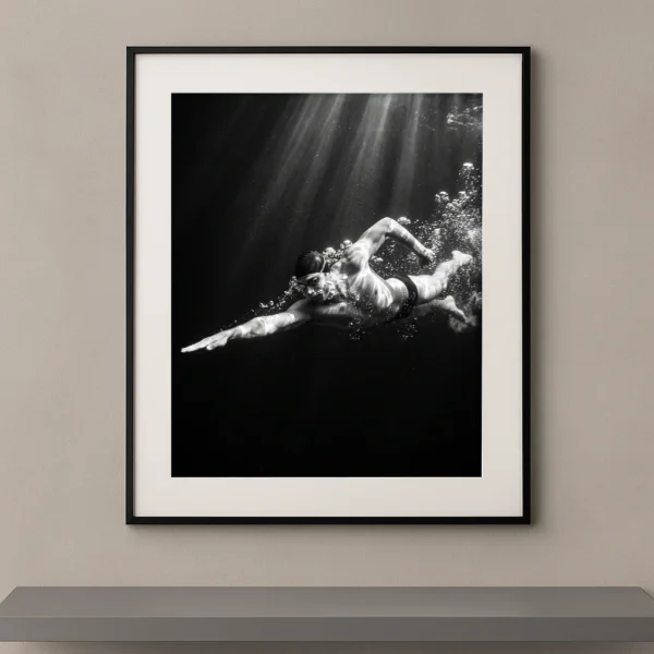 Tableau noir et blanc d’un nageur évoluant sous l’eau dans un faisceau de lumière