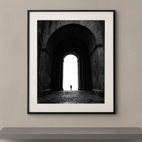 Tableau noir et blanc d’une silhouette humaine sous une immense arche monumentale