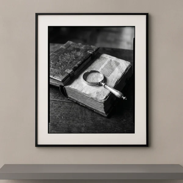 Tableau noir et blanc d'un livre ancien ouvert avec une loupe en argent