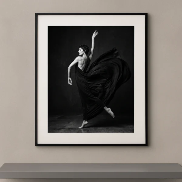 Tableau noir et blanc d'une danseuse enveloppée dans un spectaculaire mouvement de tissu sombre