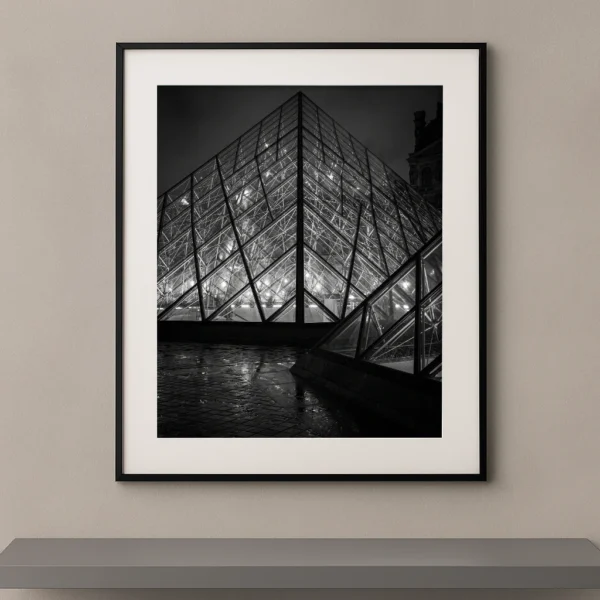 Tableau noir et blanc de la pyramide du Louvre illuminée de nuit à Paris