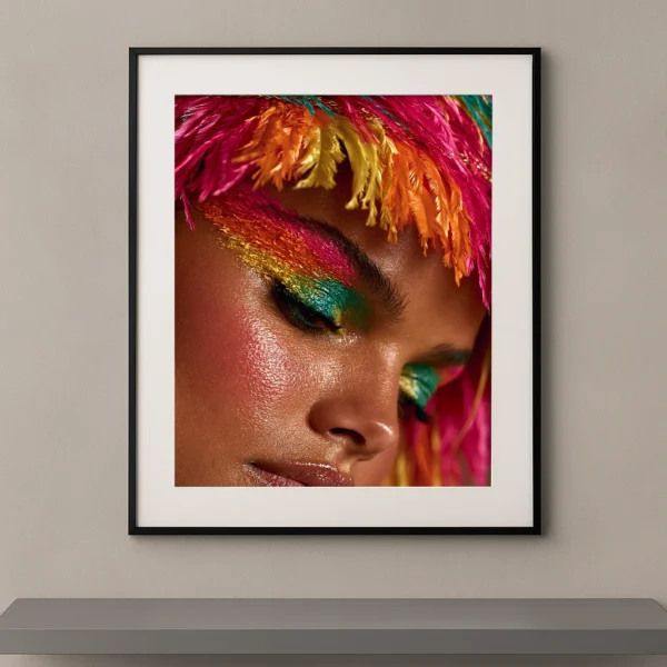 Portrait artistique en gros plan d'une femme portant un maquillage tropical multicolore avec plumes roses, orange et jaunes inspiré de la haute couture.