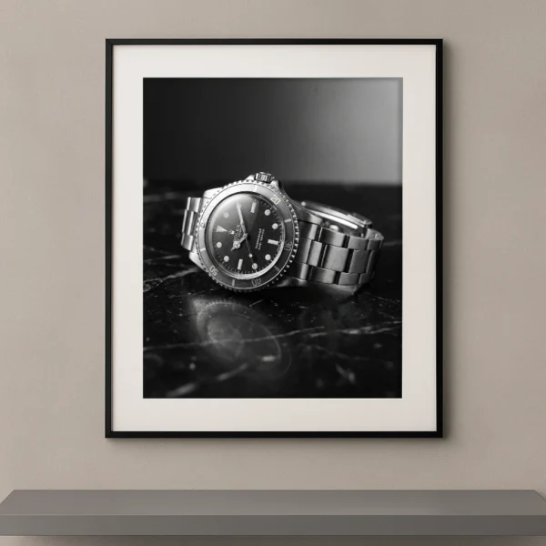 Tableau noir et blanc d’une montre Rolex Submariner vintage posée sur du marbre noir