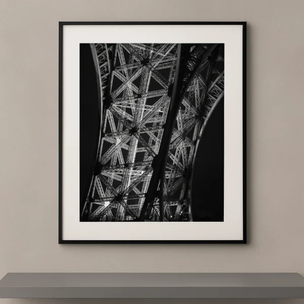 Tableau noir et blanc des structures métalliques de la Tour Eiffel vues en contre-plongée