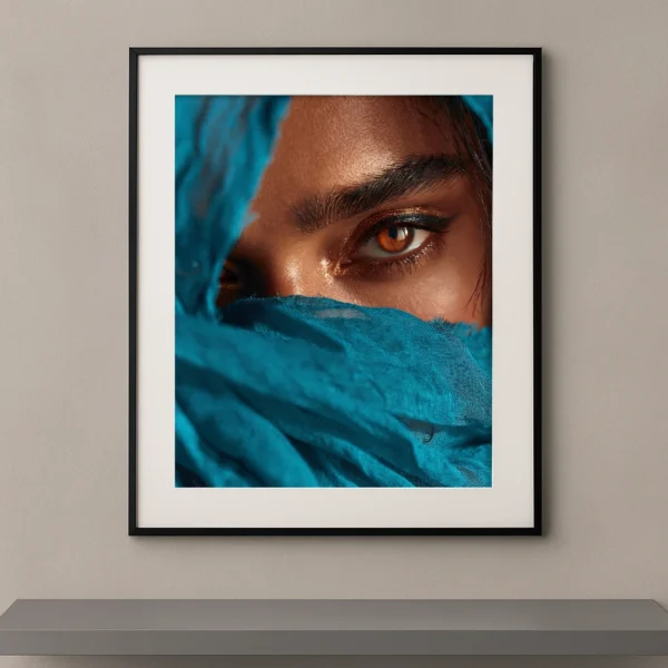 Portrait artistique d'un regard ambré intense apparaissant derrière un voile turquoise dans un style photographique Fine Art contemporain.