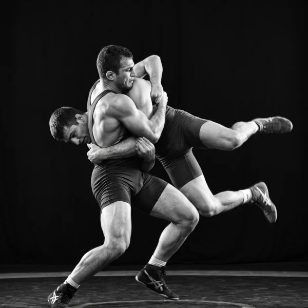 Affrontement — deux lutteurs en pleine projection, corps imbriqués sur fond noir, photographie sportive, art mural premium