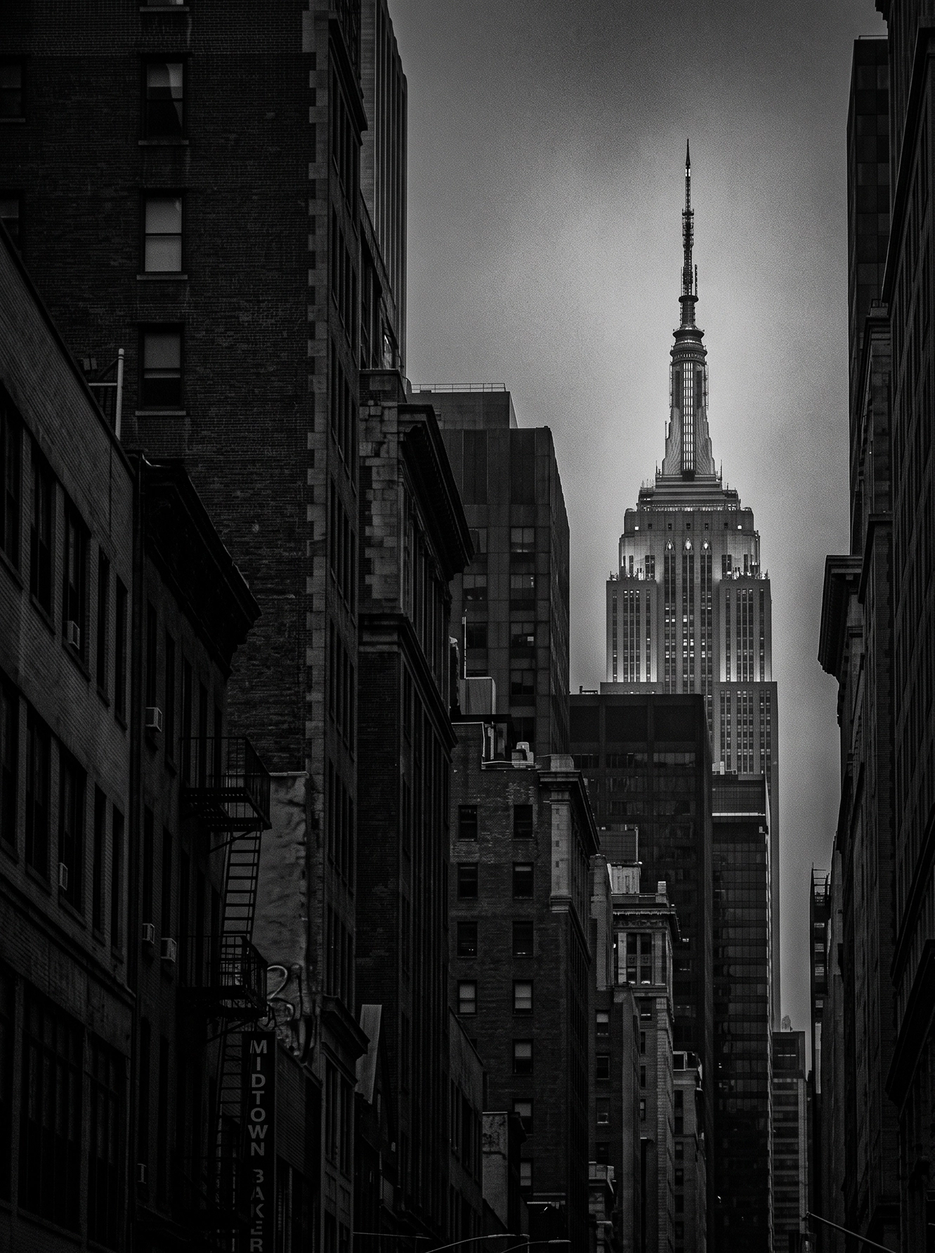 Empire State Perspective — gratte-ciel Empire State surgissant d'un canyon urbain, noir et blanc, art mural premium