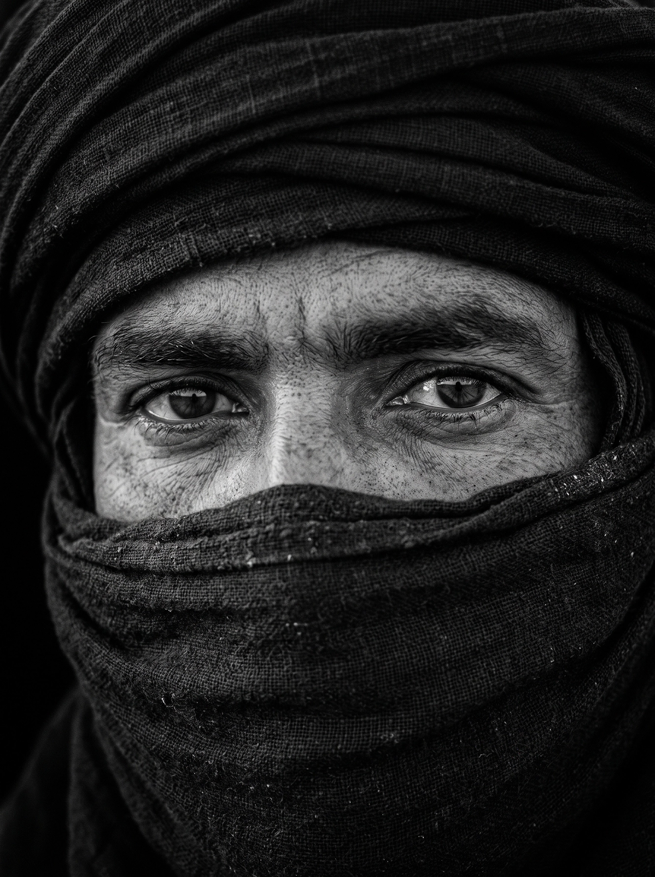 Les Yeux du Désert — portrait touareg concentré sur le regard entouré du voile, noir et blanc, art mural premium