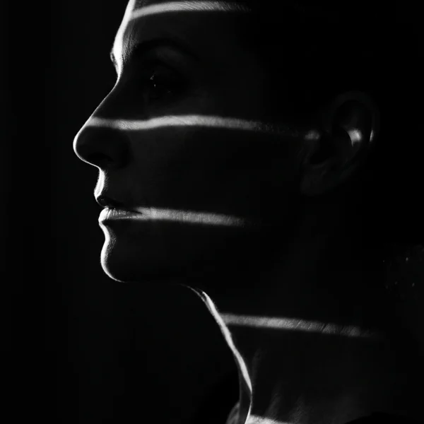 Lignes de Lumière — visage féminin dans l'obscurité traversé de fines bandes lumineuses, noir et blanc, art mural premium