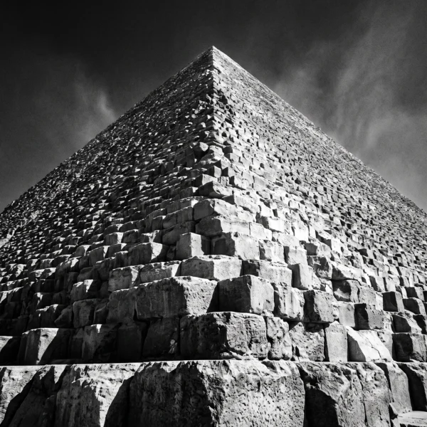 Pyramide de Gizeh Éternelle — pyramide de Gizeh en contre-plongée, blocs de pierre et ciel dramatique, noir et blanc, art mural premium